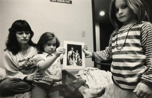 Mary & her daughters holding a family portrait with their father, Minneapolis, 1987